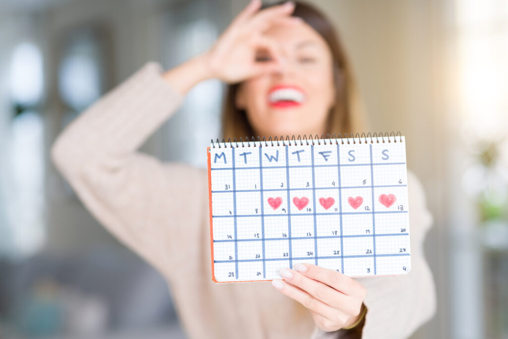 Happy woman holding menstruation calendar 