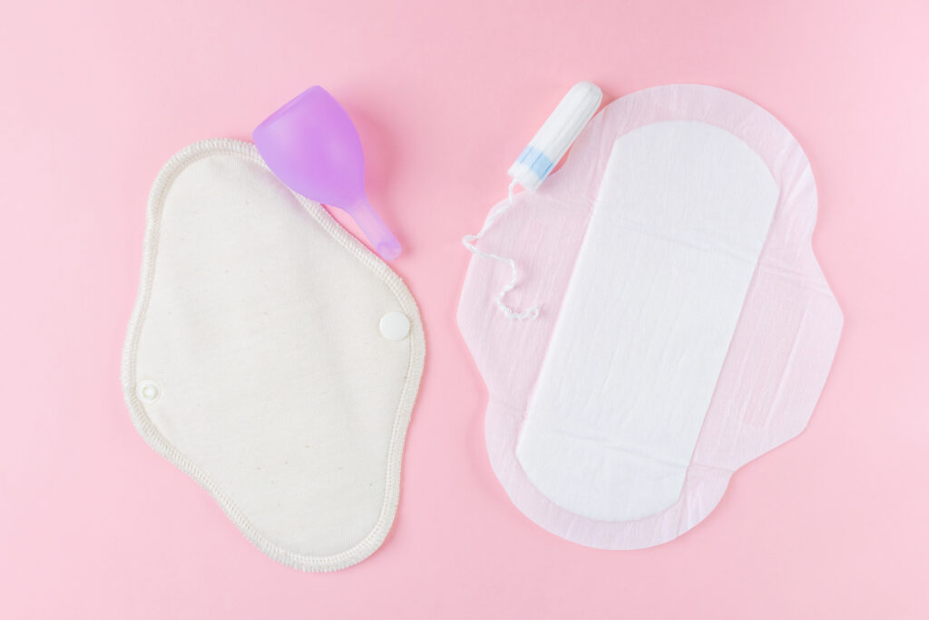 Reusable eco-friendly female pad, menstrual cup, tampon and usual women's pad. Pink background, place for text, minimalism, top view, flat lay. Zero waste concept