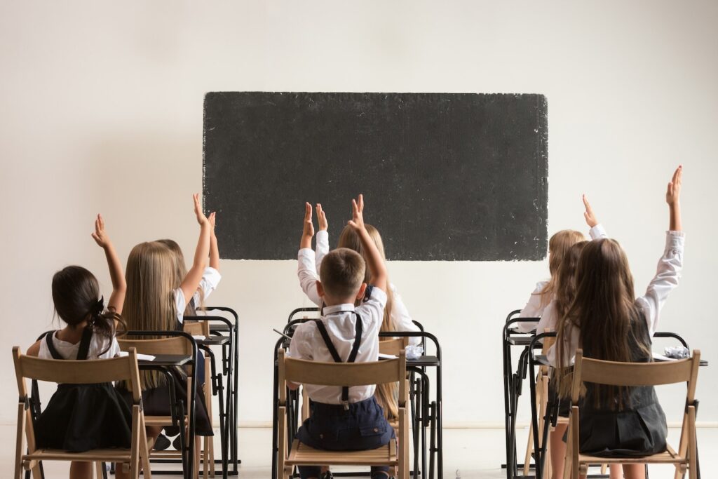 students putting hands up in classroom