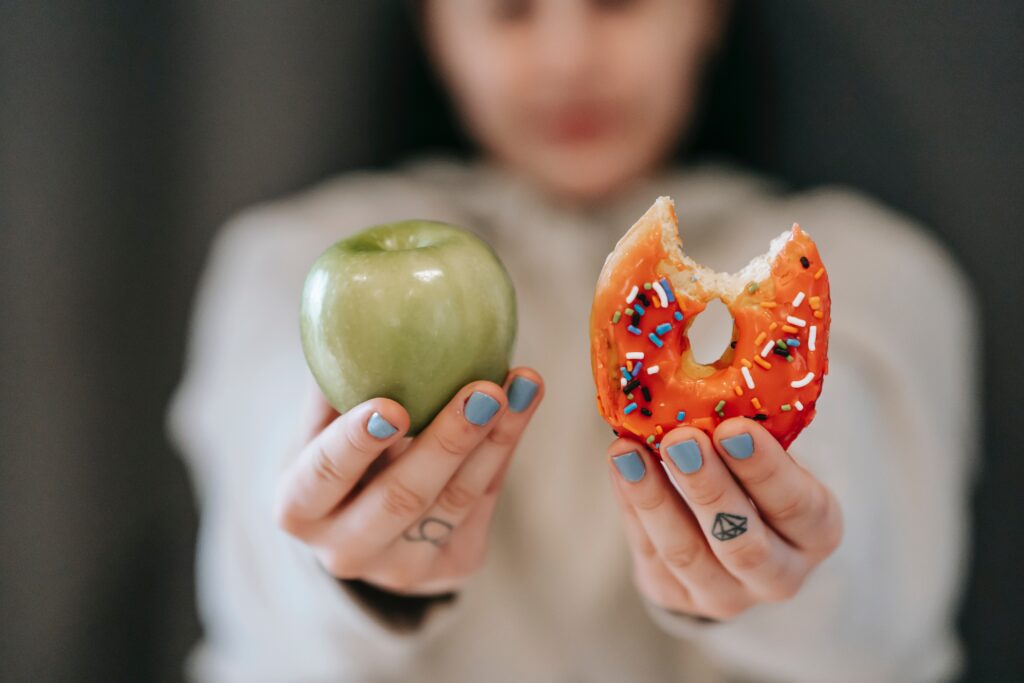 Woman holding apple and donut in both hands
